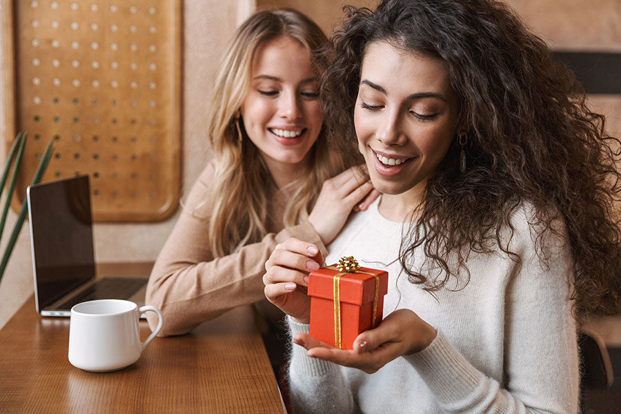 Two cheerful young girlfriends sitting at the cafe